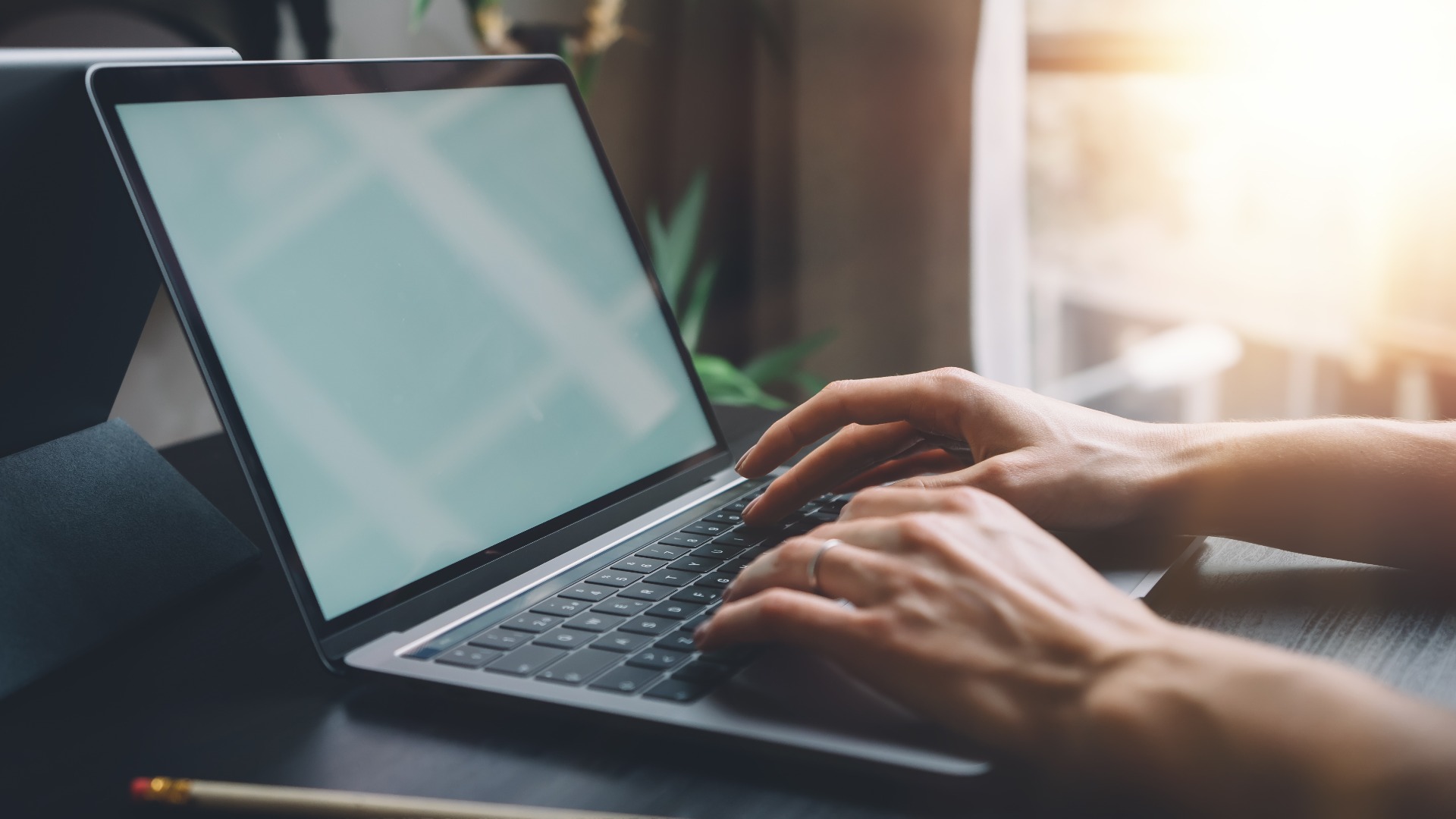 Female hands typing on laptop keyboard at the office. Wide